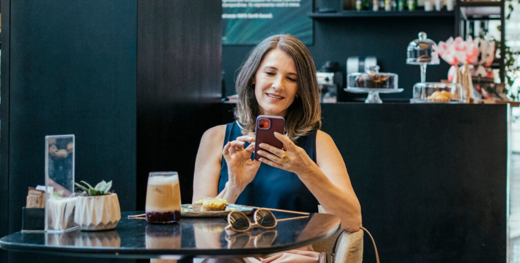 Woman at restaurant table using smartphone with LongFi Connect indoor Wi-Fi
