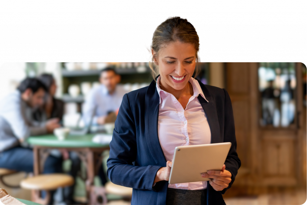 Professional woman smiling at tablet in busy café or restaurant environment
