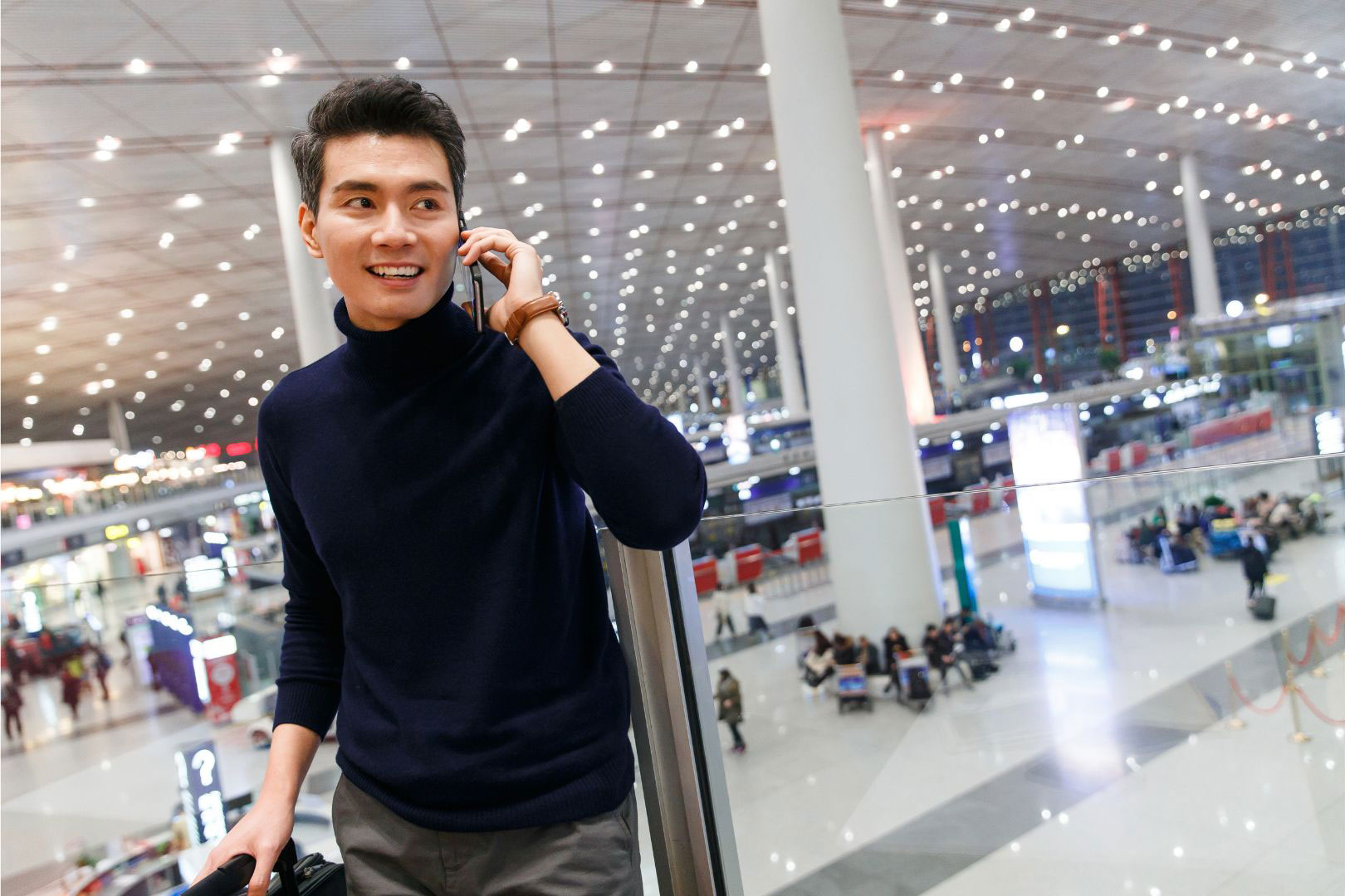 A traveler checking a phone in a calm, naturally lit airport terminal concourse